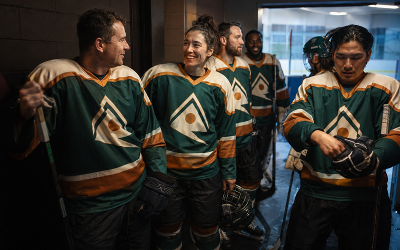 Hockey teammates in matching custom jerseys sharing a laugh in the locker room hallway